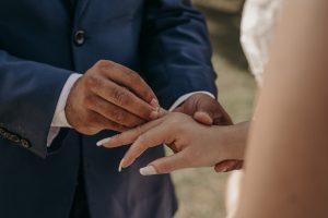 a groom putting on the wedding ring on bride s finger